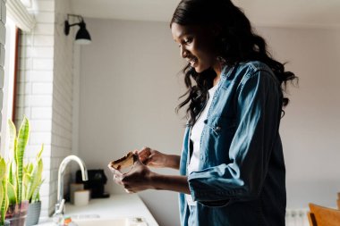 Black young woman smiling while cooking in kitchen at home