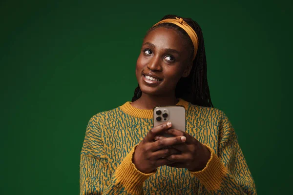Black Young Woman Pigtails Smiling While Using Cellphone Isolated Green — Zdjęcie stockowe