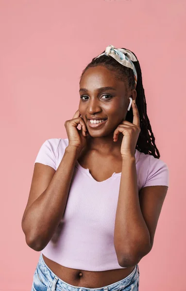 Чорна Молода Жінка Слухає Музичні Навушники Посміхається Ізольовано Над Рожевою — стокове фото