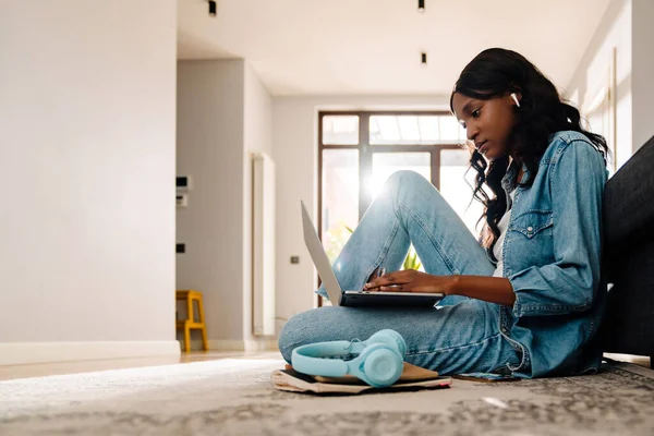 Black Young Woman Earphones Using Laptop While Sitting Floor Home — Stockfoto