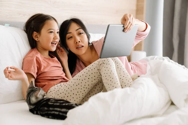 Asian Mother Daughter Using Tablet Computer While Sitting Bed Home — Stok fotoğraf