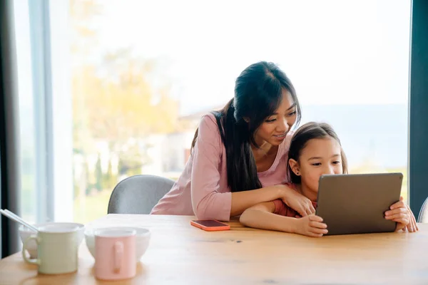 Asian Woman Her Daughter Using Tablet Computer While Sitting Table — Stock fotografie