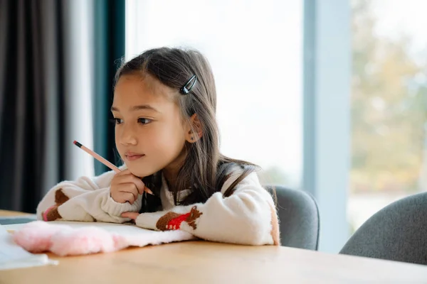 Asian Girl Doing Homework While Sitting Table Home — Stockfoto