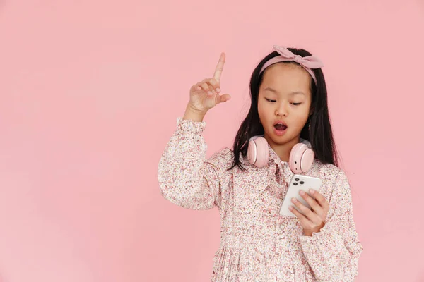 Азійська Шокована Дівчинка Жестикулює Користуючись Мобільним Телефоном Ізольованим Рожевому Фоні — стокове фото