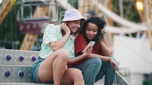 Дві Позитивні Багатонаціональні Молоді Жінки Дивляться Мобільні Розмовляють Парку Пригод — стокове відео