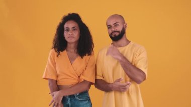 Meditative hispanic couple disagreeing with something in the yellow studio
