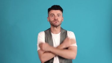 Worried brunet man wearing a vest and t-shirt getting upset about losing in the blue studio
