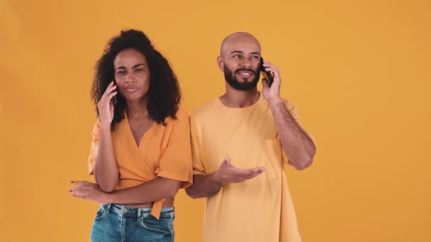Smiling Hispanic Couple Talking Phone Gesturing Yellow Studio – Stock-video