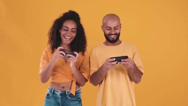 Positive Hispanic Couple Playing Video Game Phone Yellow Studio — Stockvideo