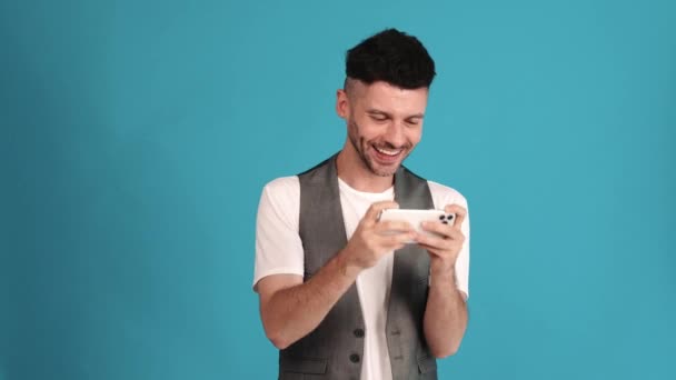 Smiling Brunet Man Wearing Vest Shirt Playing Video Game Phone — Stockvideo