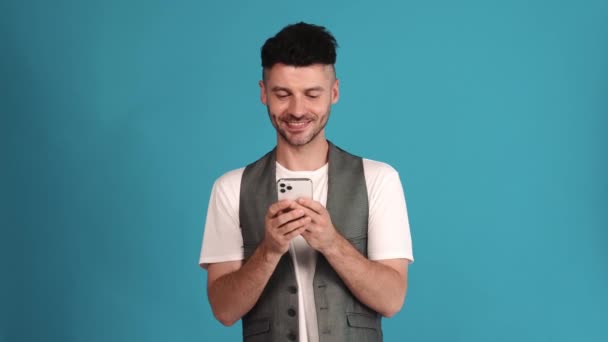 Happy Brunet Man Wearing Vest Shirt Texting Phone Blue Studio — Stock video