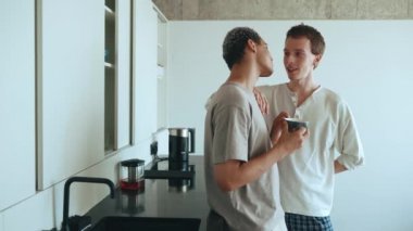 Happy multinational gay couple talking while standing in the kitchen