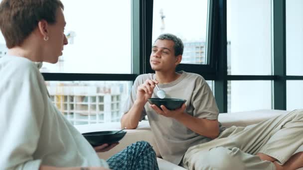 Pretty Gay Couple Eating Breakfast Talking While Sitting Sofa Home — Vídeo de Stock