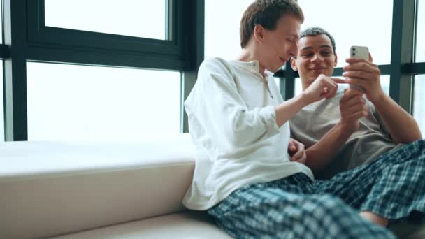 Smiling Gay Couple Looking Phone Talking While Sitting Sofa Home — Vídeo de Stock