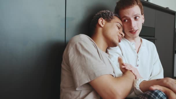 Lovely Multinational Gay Couple Talking While Sitting Kitchen Floor — Vídeo de Stock