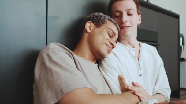 Positive Multinational Gay Couple Hugging Kissing While Sitting Kitchen Floor — ストック動画