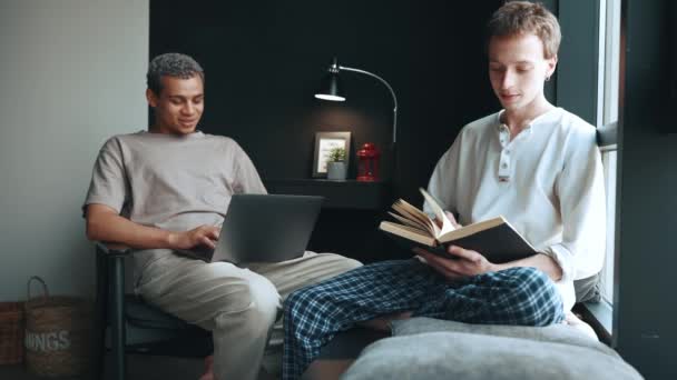 Pretty Multinational Gay Couple Working Laptop Reading Book While Talking — Stock Video