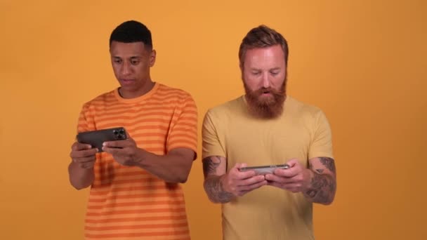 Upset Multinational Men Playing Digital Game Phones While Standing Yellow — Stockvideo