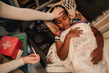 Mother measuring temperature while taking care of your sick son at home