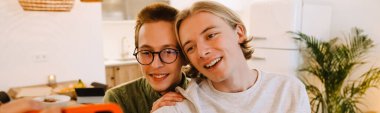 European gay couple hugging and smiling while spending time together at home