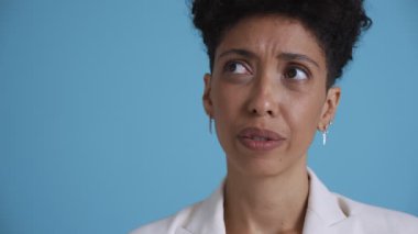 Face of pensive hispanic curly haired woman thinking in the blue studio