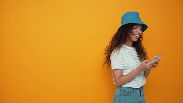Smiling Brunette Curly Haired Woman Wearing Panama Hat Typing Mobile — Stok video