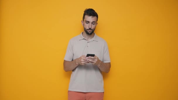 Laughing Brunet Man Wearing Shirt Typing Mobile While Standing Yellow — Stock video