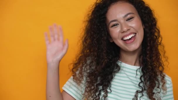 Cheerful Brunette Curly Haired Woman Waving Hand Camera Yellow Studio — Vídeos de Stock