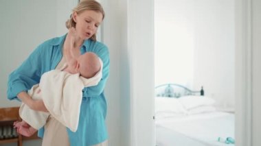 Sad blonde mother talking with her small child in her arms indoors at home
