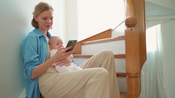 Positive Blonde Mother Typing Phone Her Small Child Her Arms — Wideo stockowe