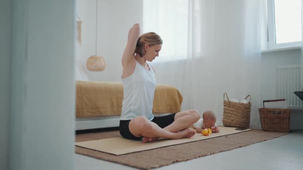 Concentrated Blonde Mother Doing Yoga Exercise While Her Small Child — Stock Video
