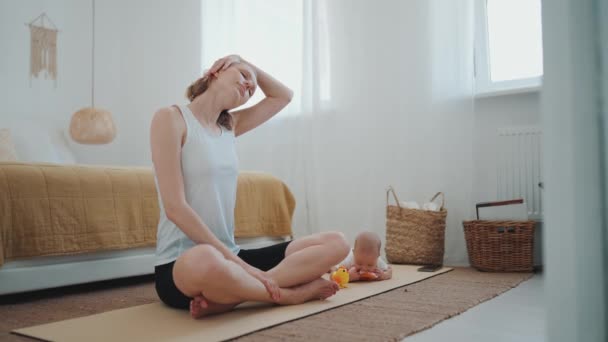 Concentrated Blonde Mother Stretching Neck While Her Small Child Lying — Wideo stockowe