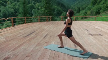 Pleased African sporty woman doing yoga meditation in the mountains outdoors