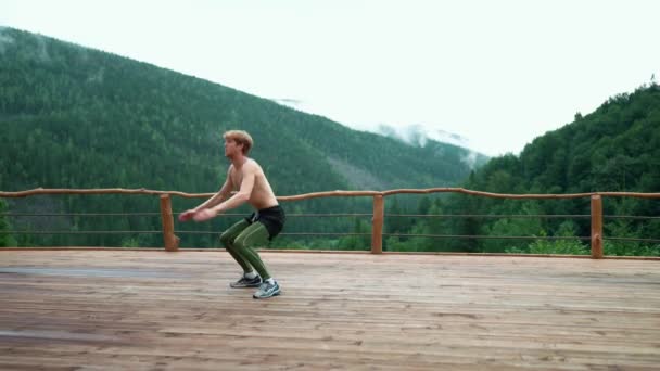 Serious Ginger Sporty Man Does Jump Squats Mountains Outdoors — Stock videók