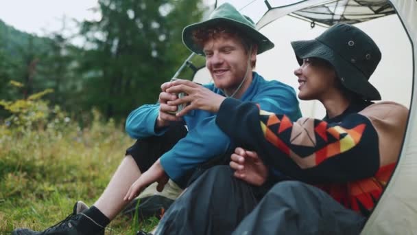 坐在山中的帐篷里喝茶的多国旅游夫妇笑着 — 图库视频影像
