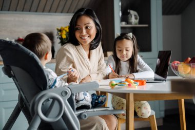 Mutlu anne evde çocuklarıyla vakit geçirirken gülümsüyor.