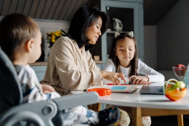 Mutlu anne evde annesiyle ödev yaparken gülümsüyor.