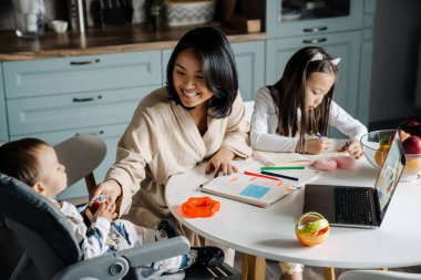 Mutlu anne evde çocuklarıyla vakit geçirirken gülümsüyor.