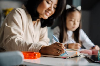 Mutlu anne evde annesiyle ödev yaparken gülümsüyor.