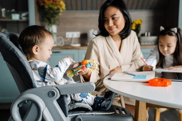Mutlu anne evde çocuklarıyla vakit geçirirken gülümsüyor.