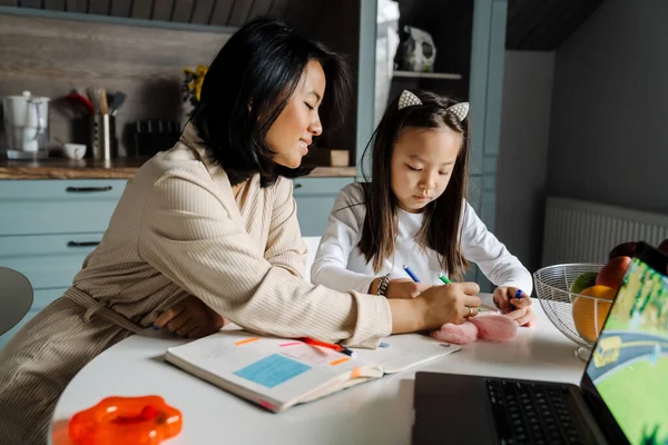 Mutlu anne evde annesiyle ödev yaparken gülümsüyor.