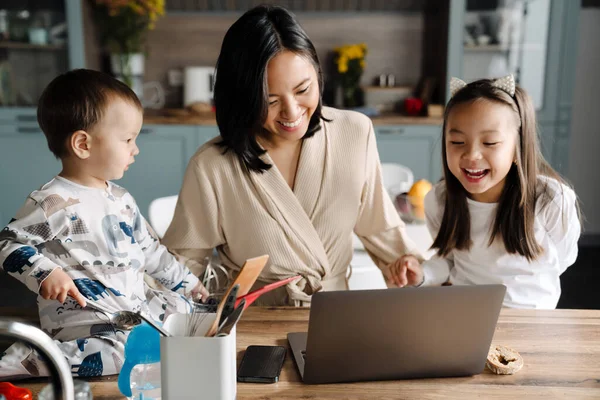 快乐的亚洲家庭一边笑着 一边用笔记本电脑 同时在家里呆着 — 图库照片