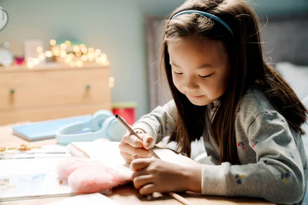 Asiatisches Mädchen Schreibt Hausaufgabenheft Während Hause Hausaufgaben Macht — Stockfoto