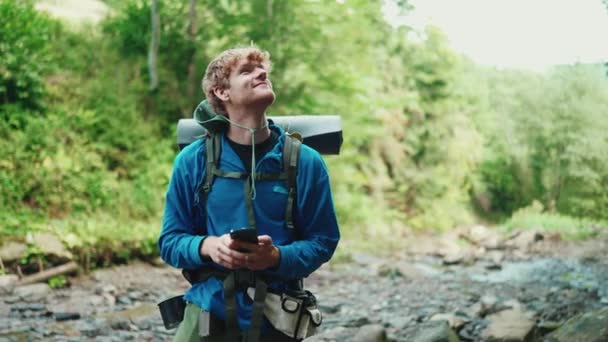 Счастливого Рыжеволосого Туриста Печатающего Мобильном Телефоне Осматривающего Реку Горах — стоковое видео