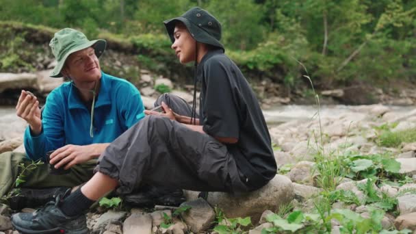 笑着的跨国旅游夫妇 一边喝茶一边看高山上的石头 — 图库视频影像