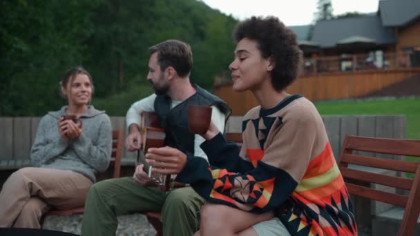 Mutlu Çokuluslu Arkadaşlar Dağlarda Ateşin Etrafında Otururken Gitar Çalıp Konuşuyorlar — Stok video