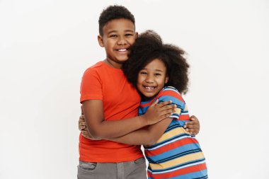 Siyah erkek ve kız, beyaz arka planda izole edilmiş kameraya gülümseyip sarılıyorlar.