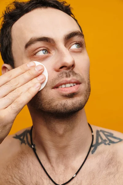 Sarı duvarın üzerinde pamuk kullanan orta yaşlı bir adamın portresini kapat.