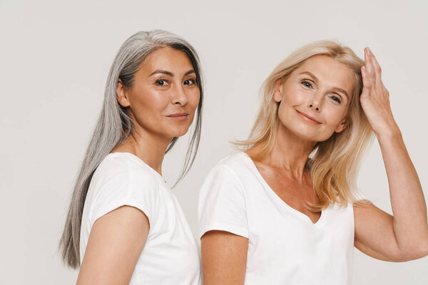 Mature multiracial women with gray hair wearing t-shirts posing at camera isolated over white background