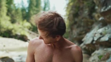 Komik turist kızıl saçlı adam dağlarda nehirde dururken başını sallıyor.